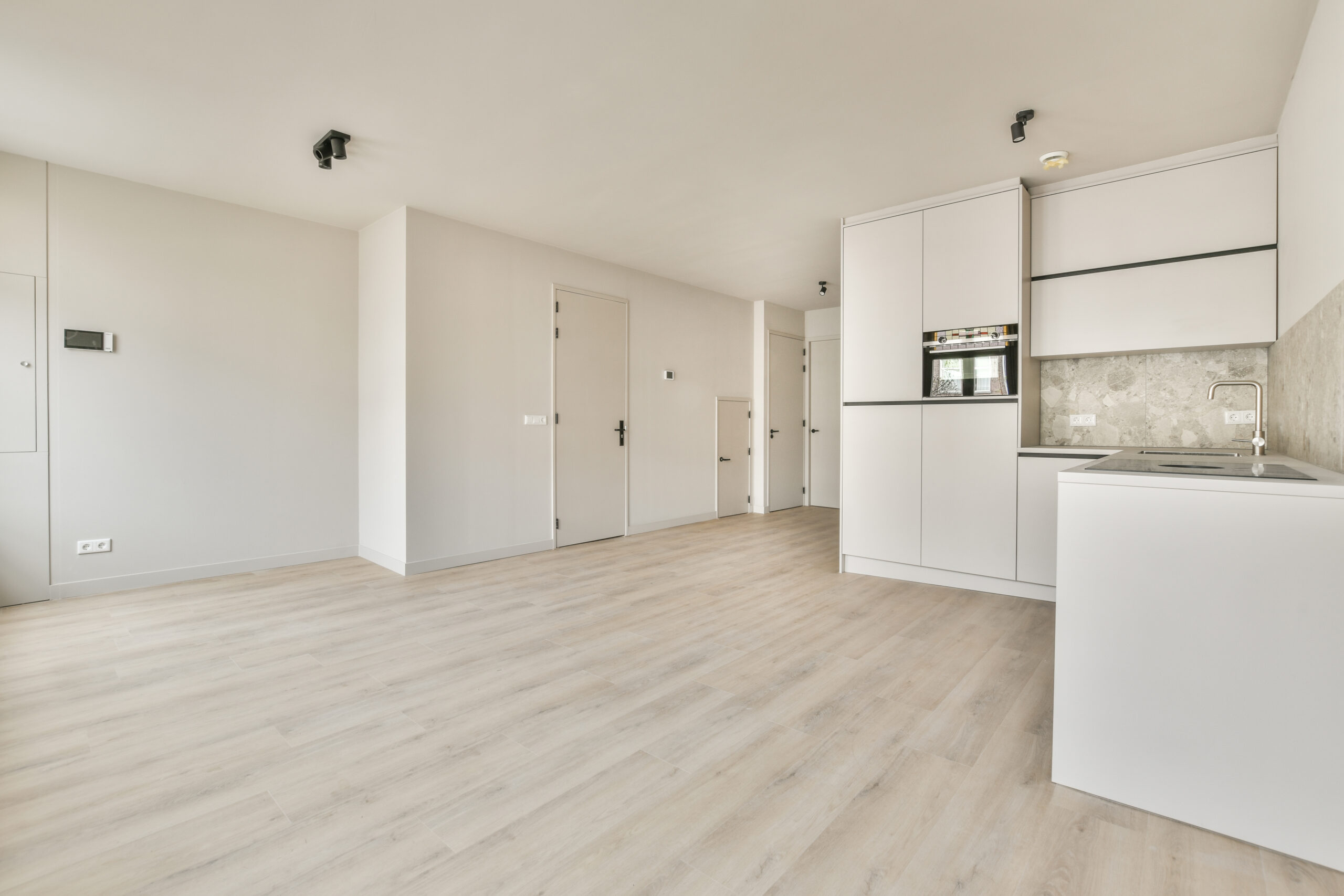 An empty room with a window and a kitchen corner