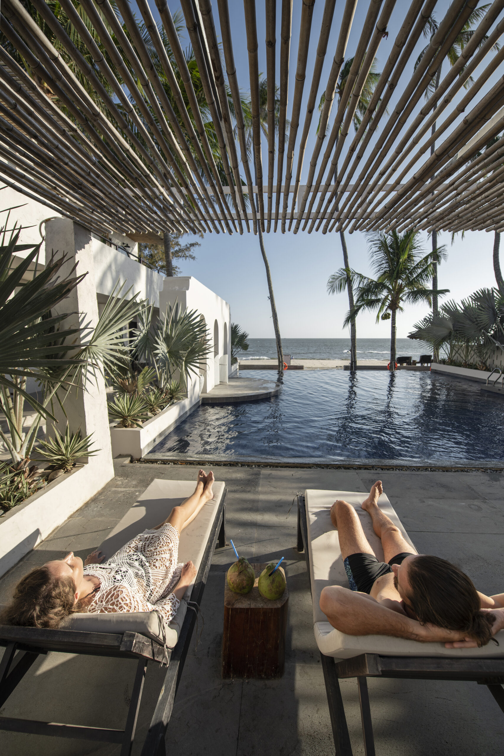 couple-talking-drinking-coconut-milk-by-pool-vacation