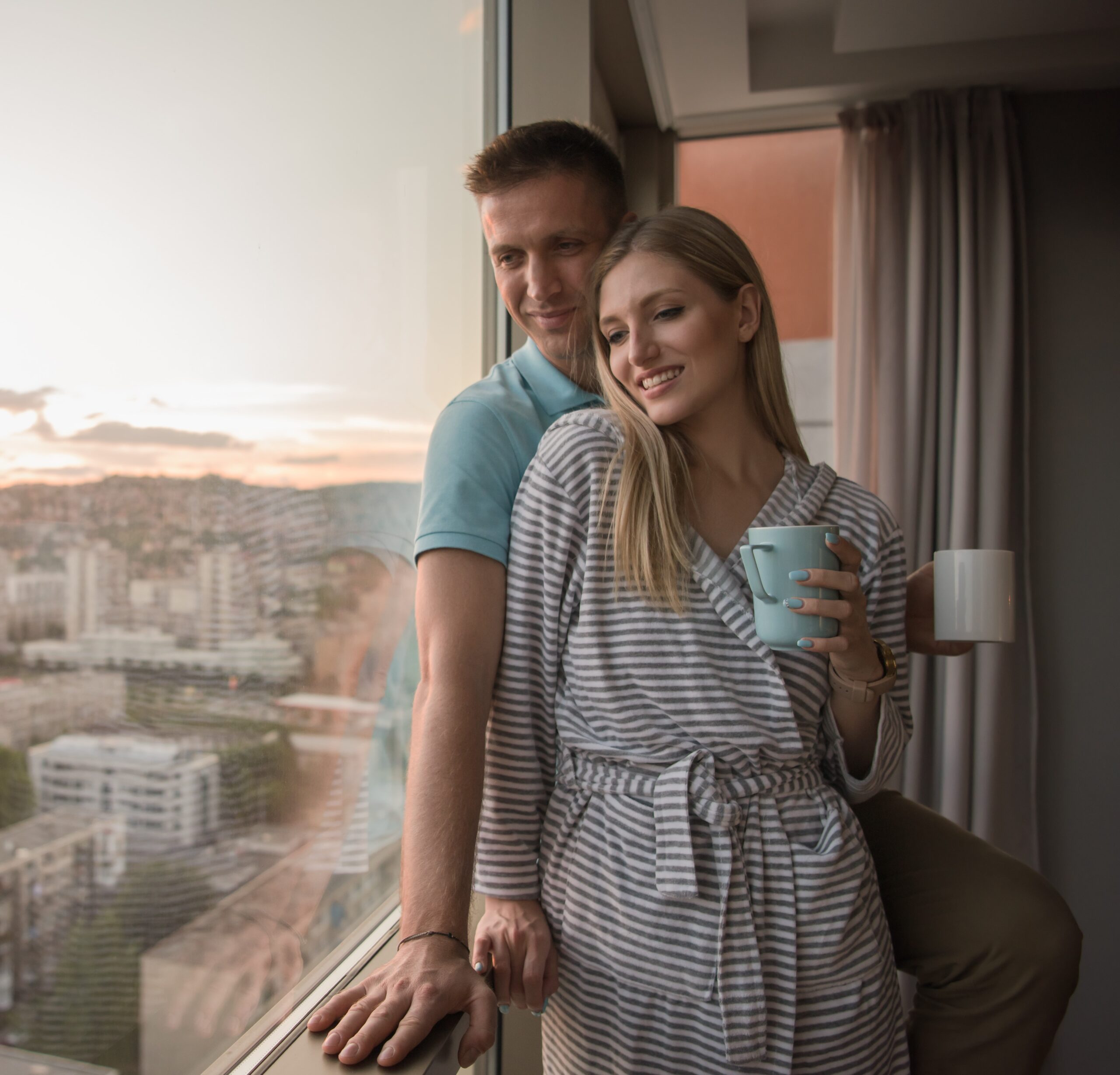 young couple enjoying evening coffee by the window