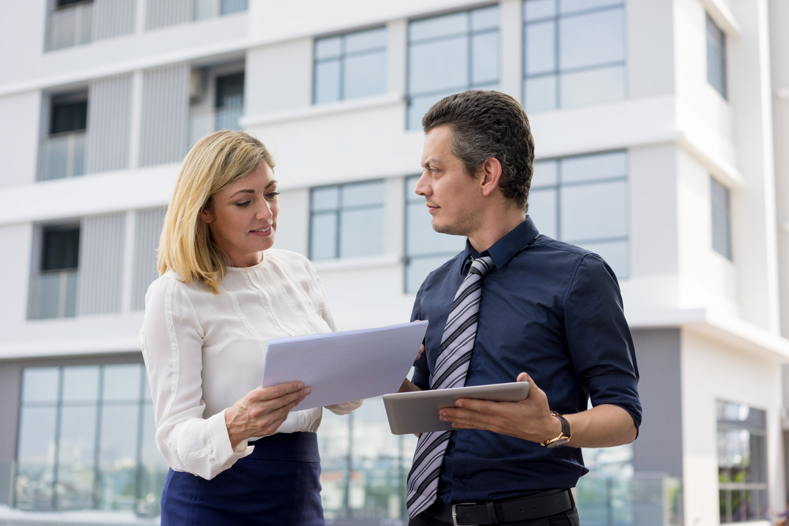 Content business partners discussing documents outdoors