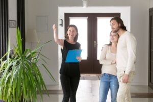 Tres personas de pie en el pasillo Agente inmobiliario sonriente agente inmobiliario que muestra la casa de la propiedad en venta o inquilino a una pareja casada joven feliz Nueva mudanza de casa y préstamo inmobiliario y concepto de hipoteca