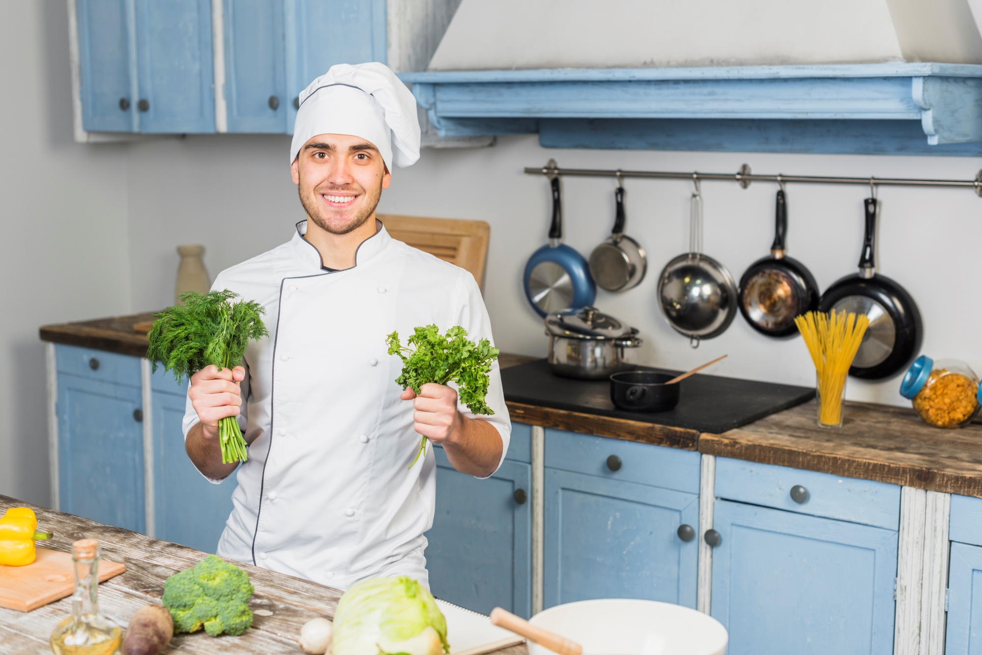 Chef en la cocina azul frente a las verduras