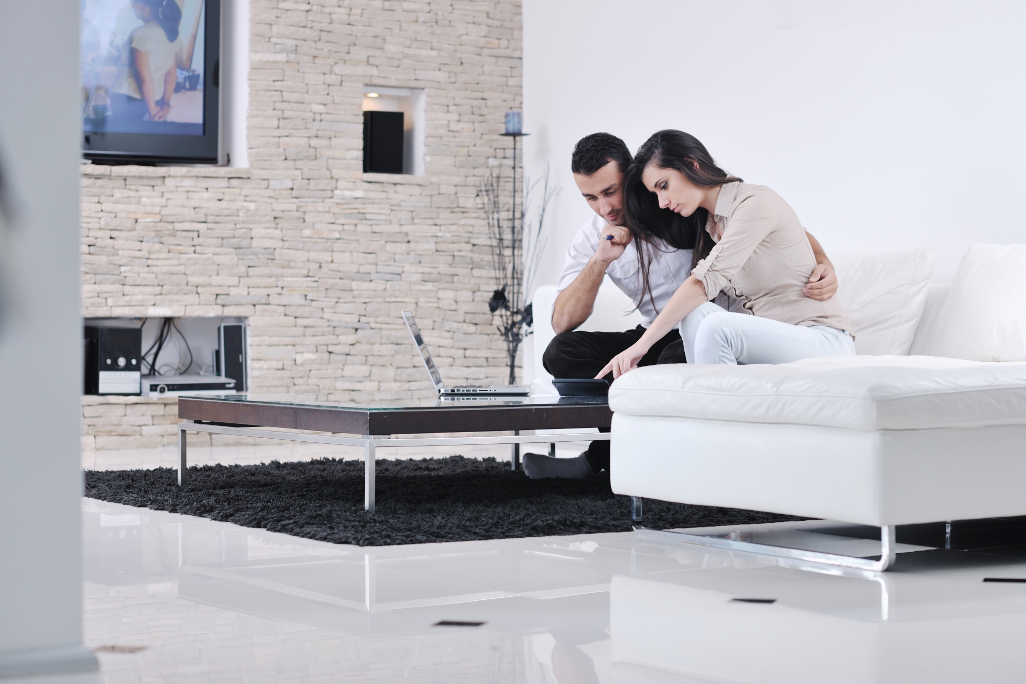 La pareja alegre se relaja y ve una pelicula en la computadora portátil en la sala de estar moderna en el interior de la casa