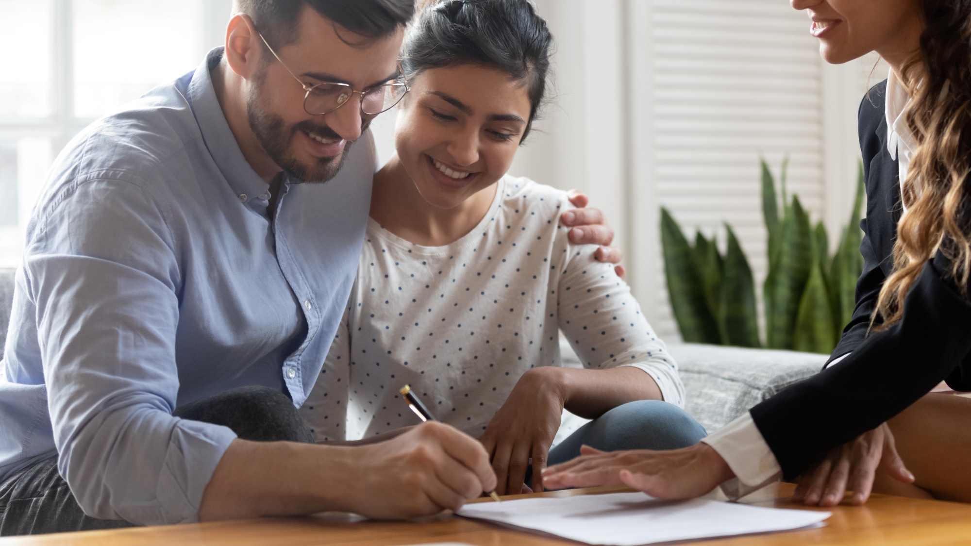 Pareja firma contrato de compra venta de casa con agente inmobiliario