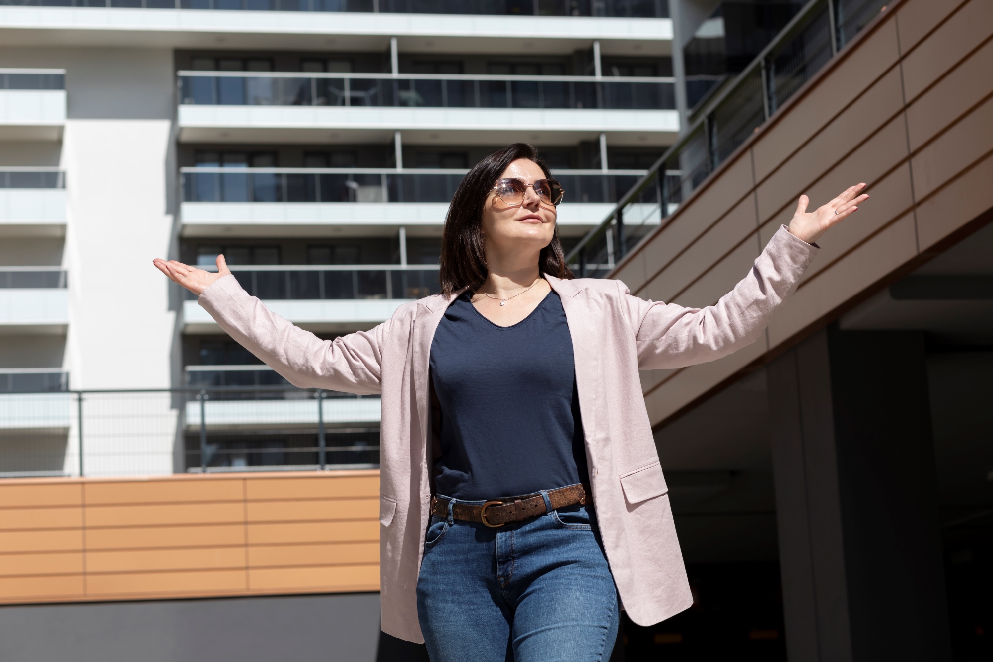 Mujer-madura-con-brazos-abiertos-disfruta-de-un-moderno-complejo-de condominios o departamentos