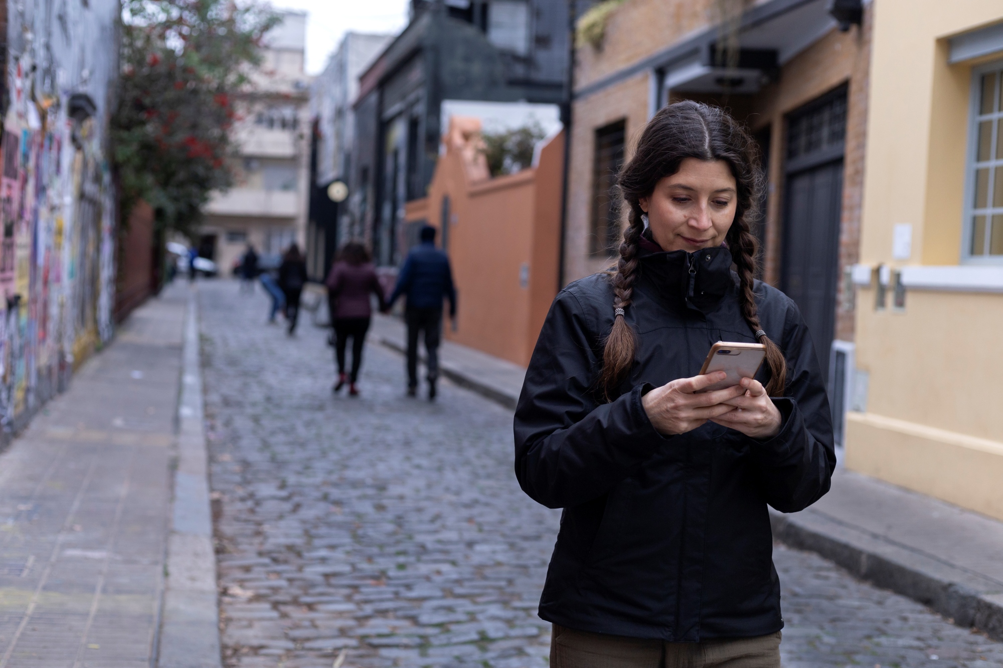 Joven caminando por su nuevo desarrollo residencial con el móvil en mano usando un mapa digital.