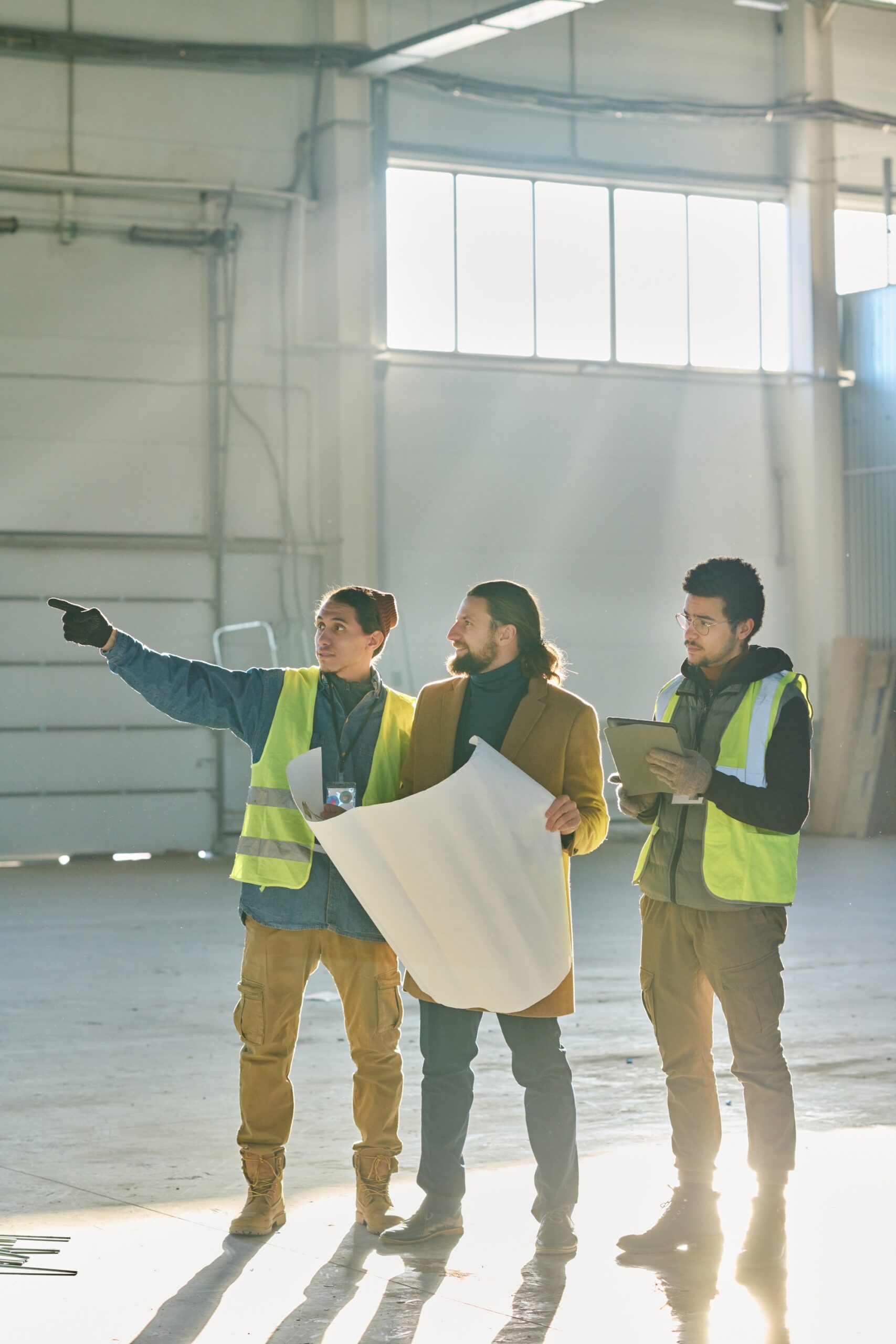 Grupo de ingenieros e inversionista revisando la remodelación de la nave industrial
