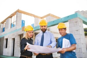 Construcción de vivienda arquitectos y trabajadores de obra revisando planos para aplicarlos en el proceso constructivos