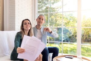 Feliz y sonriente joven pareja mostrando el contrato firmado y las llaves de su casa