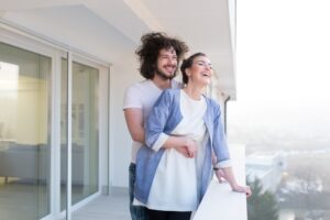 Pareja enamorada compartiendo emociones y felicidad mientras se abrazan en el balcón de su nuevo departamento