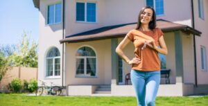 Mujer feliz mostrando s}las llaves de su nueva residencia de fondo se ve la propiedad comprada