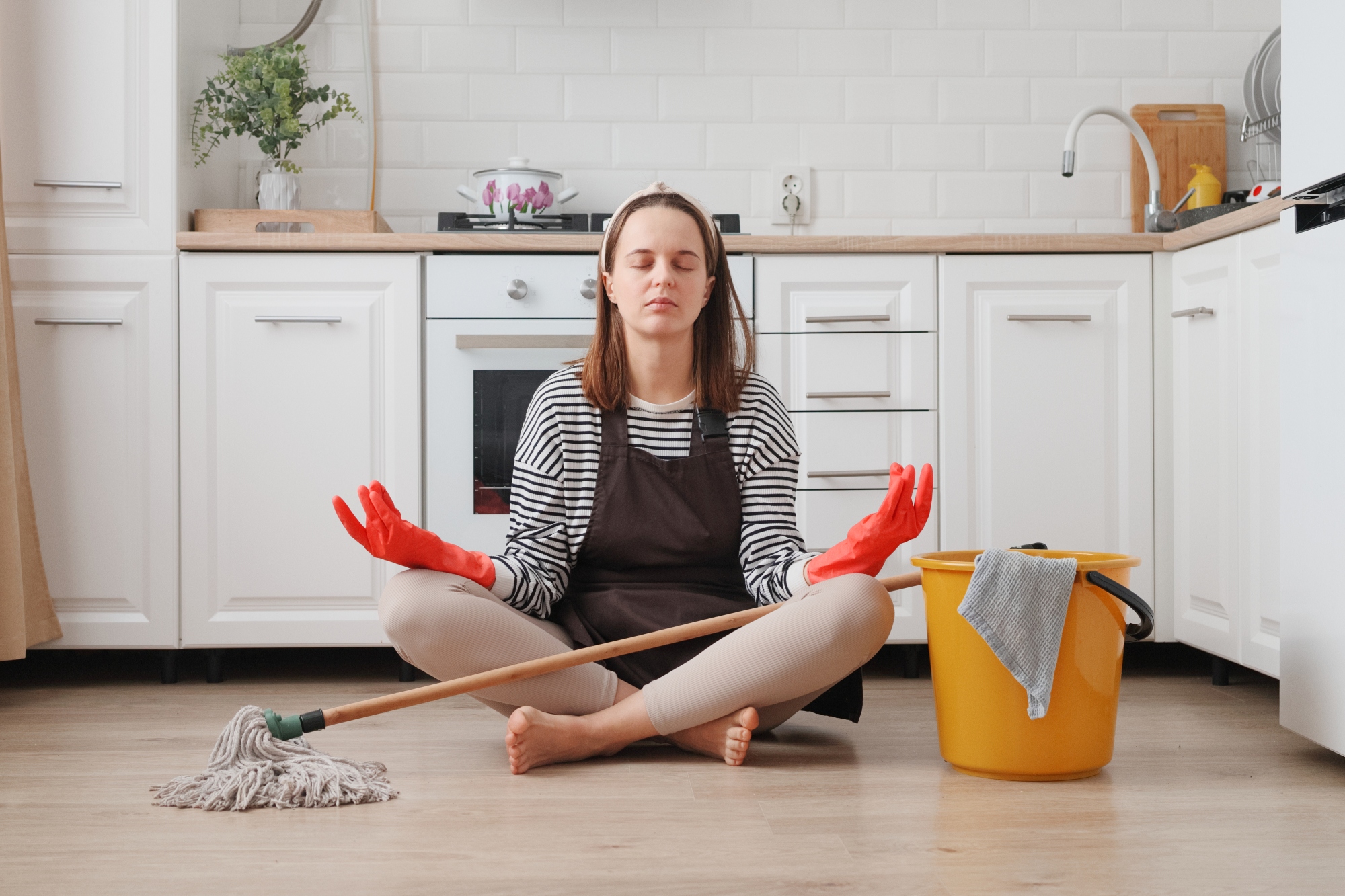 Mujer realizando la limpieza del hogar toma un descanso de la limpieza y se pone a meditar