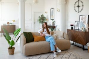 Sala de estar mujer hermosa sentada en el mueble que le da la espalda a la puerta perdiendo contacto de quien entra y quien sale