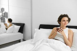 joven descansando en su habitación acostada en la cama disfrutando una taza de café y esta se refleja en el espejo de la recamara