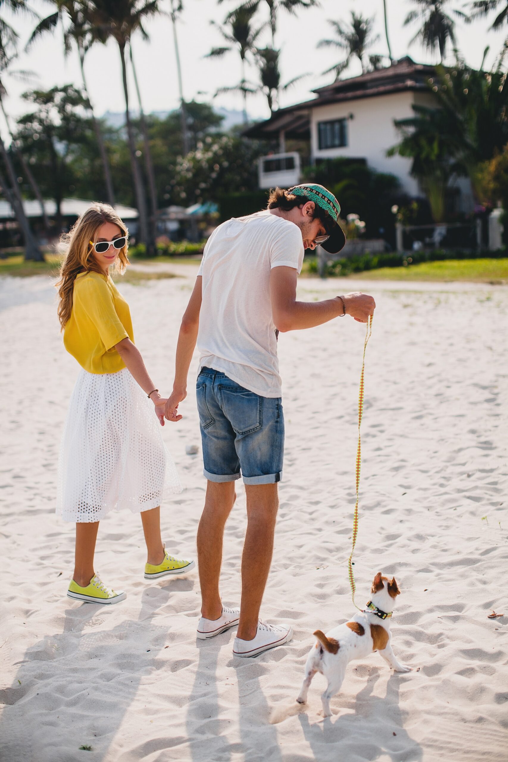 pareja-de-hipster-con-estilo-joven-inconformista-en-el-amor-caminando-y-jugando-con-el-perro-en-la-playa-tropical