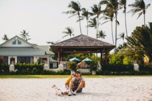 pareja-joven-sentada-en-la-arena-de-la-playa-de-fondo-su-casa-de-descanso