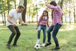 muchacha-alegre-que-juega-el-balon-de-futbol conviviendo en familia 